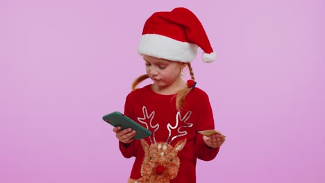 Niña-Con-Suéter-Navideño-Usa-Teléfono-Celular-Móvil,-Tarjetas-Bancarias-De-Crédito-De-Plástico,-Gana,-Calibra,-Guau