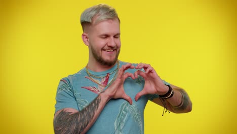 Smiling-tourist-man-makes-heart-gesture-demonstrates-love-sign-expresses-good-feelings-and-sympathy