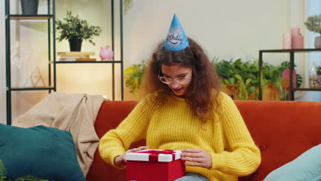 Niña-Feliz-Sostiene-Una-Caja-De-Regalo-De-Cumpleaños-Con-Cinta,-Celebrando-La-Fiesta,-Abriendo-El-Regalo-En-Casa