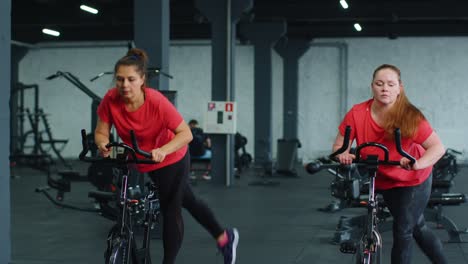 Grupo-De-Mujeres-Atléticas-Montando-En-Rutina-De-Entrenamiento-De-Bicicleta-Estacionaria-Giratoria-En-El-Gimnasio,-Pérdida-De-Peso-En-Interiores