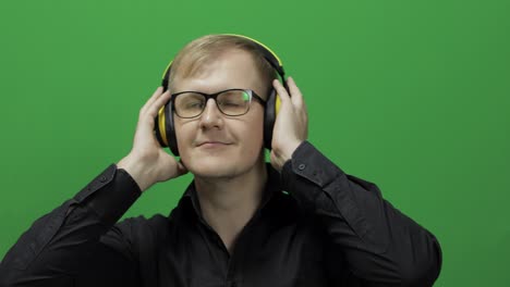 Guy-listens-to-music-in-wireless-yellow-headphones-and-dances.-Chroma-key