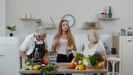 Niña-Midiendo-Con-Cinta-Métrica-Su-Delgada-Cintura-Y-Fanfarroneando-Frente-A-Sus-Abuelos.-Dieta-De-Alimentos-Crudos