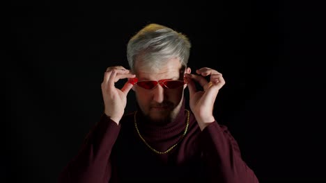 Portrait-of-seductive-young-man-in-trendy-stylish-clothes-wearing-red-sunglasses-on-black-background