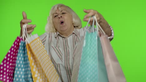 Abuela-Mayor-Levantando-Bolsas-De-Compras,-Celebrando,-Satisfecha-Con-La-Compra,-Descuento.-Clave-De-Croma