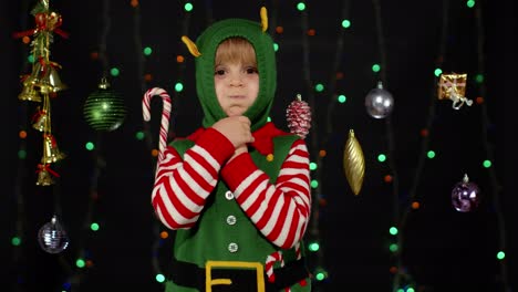 Kid-girl-in-Christmas-elf-Santa-helper-costume-dancing,-fooling-around.-New-Year-holiday-celebration