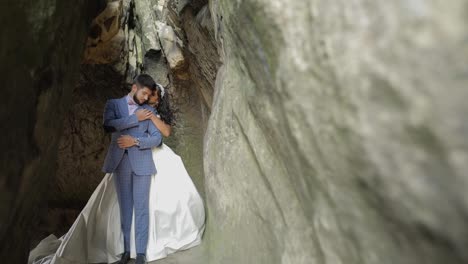 Groom-with-bride-standing-in-cave-of-mountain-hills.-Wedding-couple-in-love