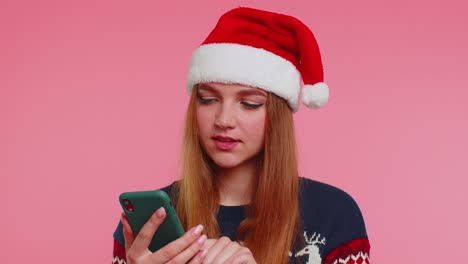 Mujer-Con-Elegante-Suéter-Navideño-Mirando-La-Pantalla-Del-Teléfono-Inteligente-Regocijándose-Sinceramente-Por-Ganar-éxito-Y-Suerte