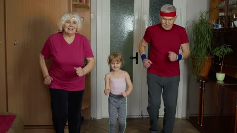 Nieta-Y-Abuelos-Maduros-En-Ropa-Deportiva-Haciendo-Ejercicios-Deportivos-Para-Correr-En-Casa