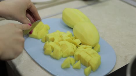 Woman-cutting-potato-on-the-blue-cutting-board