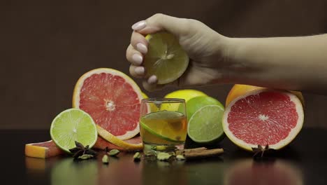 Woman-squeezes-juice-from-lemon-into-a-glass-cup-with-alcohol-cocktail