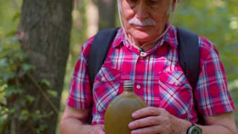 Cansado-Y-Sediento-Anciano-Anciano-Excursionista-Caucásico-Abuelo-Relajándose,-Bebiendo-Agua-En-El-Bosque-Después-De-Caminar