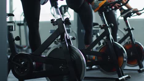 Healthy-Caucasian-group-of-women-exercising-workout-on-stationary-cycling-machine-bike-in-gym