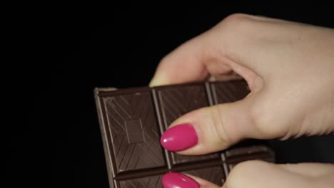 Woman-breaks-black-chocolate-bar.-Close-up.-Slow-motion