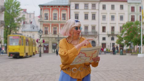 Mujer-Abuela-Turística-Con-Estilo-Caminando-Por-La-Calle,-Buscando-El-Camino-Usando-Un-Mapa-De-Papel-En-La-Ciudad