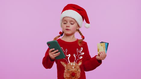 Niña-En-Suéter-Navideño-Use-Teléfono-Celular-Móvil,-Tarjetas-Bancarias-De-Crédito-De-Plástico,-Gane,-Calebrate,-Wow