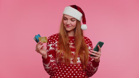 Mujer-Con-Suéter-Navideño-Usa-Teléfono-Celular-Móvil-Y-Tarjeta-Bancaria-De-Crédito-De-Plástico,-Gana,-Calibra,-Guau