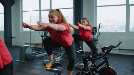 Group-of-smiling-friends-women-class-exercising,-training,-spinning-on-stationary-bike-at-modern-gym