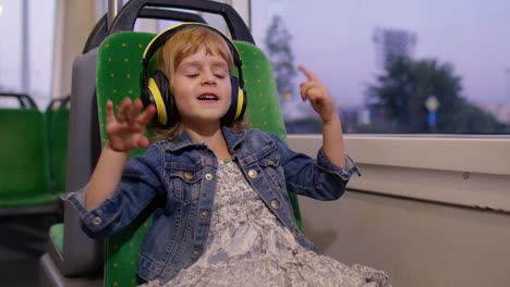 Niña-Pequeña-Con-Audífonos-Escuchando-Música,-Relájese-Bailando-Mientras-Viaja-En-Autobús-En-La-Ciudad