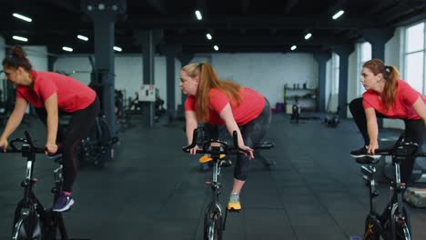 Grupo-De-Chicas-Atléticas-Realizando-Ejercicios-De-Entrenamiento-Aeróbico-En-Bicicleta-Estática-En-El-Gimnasio