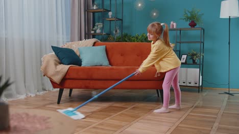 Una-Niña-Pequeña-Graciosa-Limpiando-Pisos-Con-Un-Trapeador-En-Casa-Bailando,-Cantando-De-Humor-Positivo