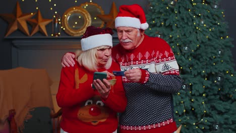 Großmutter-Einer-älteren-Familie,-Die-Mit-Kreditkarte-Und-Smartphone-Weihnachtsgeschenke-Einkauft