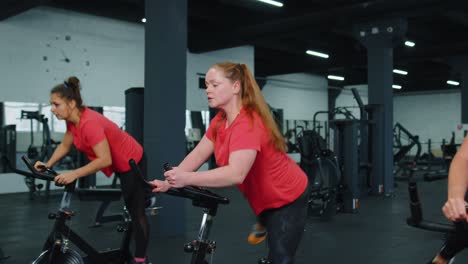 Grupo-Caucásico-Saludable-De-Mujeres-Haciendo-Ejercicio-En-Bicicleta-Estática-En-El-Gimnasio