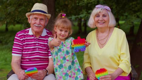 Smiling-senior-grandmother-grandfather-with-granddaughter-playing-squeezing-anti-stress-toy-game