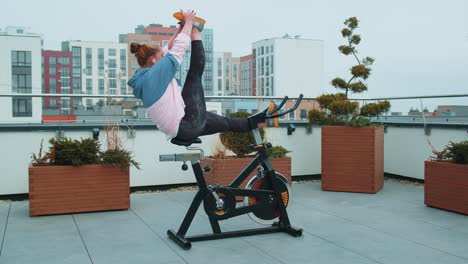 Sportliche-Frau-Macht-Schnurtrainingsroutine-Auf-Einem-Stationären-Fahrrad-Auf-Dem-Hausdach,-Gewichtsverlust