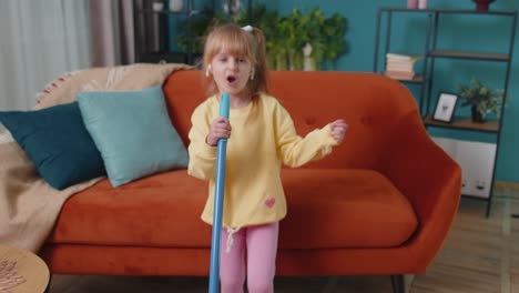 Una-Niña-Pequeña-Graciosa-Limpiando-Pisos-Con-Un-Trapeador-En-Casa-Bailando,-Cantando-De-Humor-Positivo