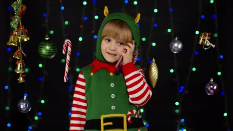 Niña-Vestida-De-Elfo-Navideño,-Disfraz-De-Ayudante-De-Papá-Noel-Haciendo-Felicitaciones,-Llamada-Por-Teléfono-Móvil