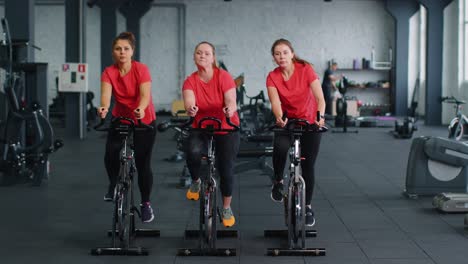 Group-of-girls-performs-aerobic-training-workout-cardio-routine-on-bike-simulators,-cycle-training