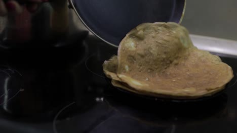 The-process-of-cooking-homemade-pancakes.-Woman-puts-pancake-from-pan-to-plate