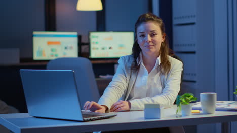 Business-woman-looking-at-camera-smiling-after-typing-on-laptop