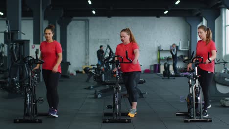 Gesunde-Kaukasische-Gruppe-Von-Frauen-Trainieren-Auf-Einem-Stationären-Fahrrad-Im-Fitnessstudio