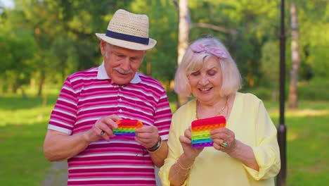 Sonriente-Mayor-Abuela-Abuelo-Jugando-Antiestrés-Pantalla-Táctil-Empujar-Pop-It-Popular-Juguete