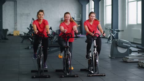 Gesunde-Kaukasische-Gruppe-Von-Frauen-Trainieren-Auf-Einem-Stationären-Fahrrad-Im-Fitnessstudio