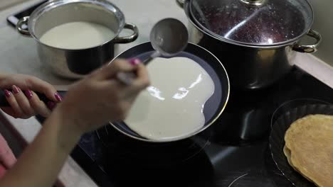 The-process-of-cooking-homemade-pancakes.-Woman-pours-pancake-dough-on-pan