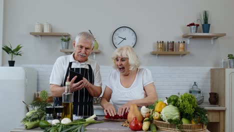 Pareja-Mayor-Cocinando-Ensalada-Con-Verduras.-Mujer-Bailando-Sosteniendo-Rodajas-Frescas-De-Pimienta-En-Los-Ojos