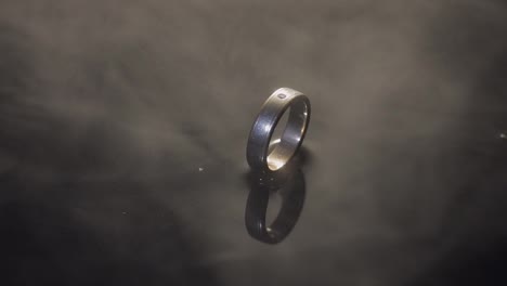 Wedding-rings-on-dark-water-surface-shining-with-light.-Close-up-macro