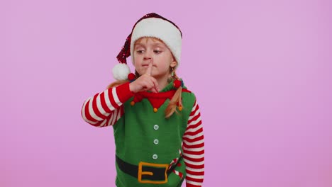 Una-Niña-Vestida-De-Elfo-Navideño-Presiona-El-Dedo-índice-Contra-Los-Labios-Y-Hace-Un-Gesto-De-Silencio,-Secreto