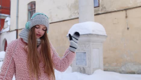 Girl-tourist-during-her-vacation-listening-to-music-via-headphones-and-dancing-in-old-city-center