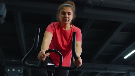 Un-Grupo-De-Chicas-Realiza-Una-Rutina-Cardiovascular-De-Entrenamiento-Aeróbico-En-Simuladores-De-Bicicletas,-Entrenamiento-En-Bicicleta.