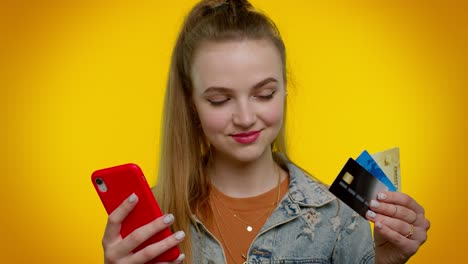 Teen-girl-using-credit-bank-cards-and-smartphone-while-transferring-money,-purchases-online-shopping