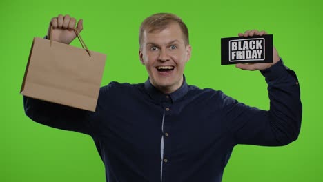 Mann-Zeigt-Einkaufstüten-Und-Aufschrift-„Black-Friday“-Und-Sieht-Erstaunt-Aus,-Weil-Er-Günstig-Eingekauft-Hat