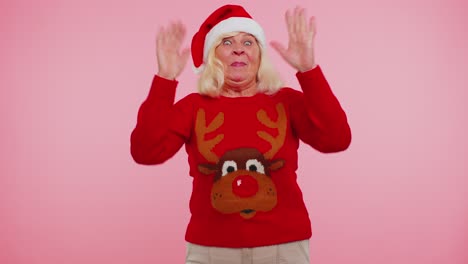 Abuela-Mujer-En-Suéter-De-Navidad-Con-Ciervos-Ondas-Palma-De-La-Mano-En-Gesto-De-Saludo-Da-La-Bienvenida-A-Alguien