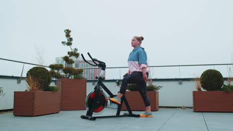 Mujer-Caucásica-Sana-Haciendo-Ejercicio-En-Una-Máquina-De-Ciclismo-Estacionaria-En-Bicicleta-En-El-Gimnasio-De-La-Azotea-De-La-Casa