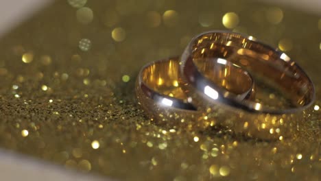 Wedding-gols-rings-lying-on-shiny-glossy-surface.-Shining-with-light.-Close-up