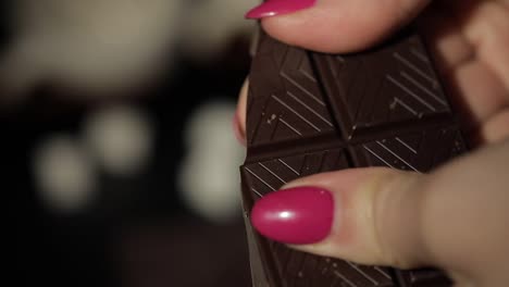 Woman-breaks-black-chocolate-bar.-Close-up.-Slow-motion