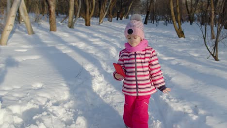 Child-girl-vlogger-making-selfies-photo-for-social-networks,-chatting-with-friends-in-winter-park