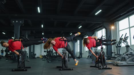 Trucos-De-Entrenamiento-En-Grupo-De-Mujeres-Atléticas-En-La-Rutina-De-Bicicleta-Estacionaria-Giratoria-En-El-Gimnasio,-Pérdida-De-Peso-En-Interiores